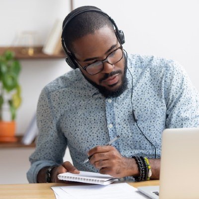 Man studying at desk with headphones on.